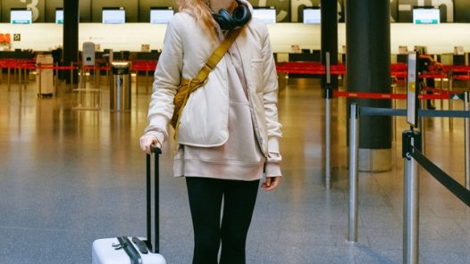 Girl wearing a mask and pulling a suitcase in an airport